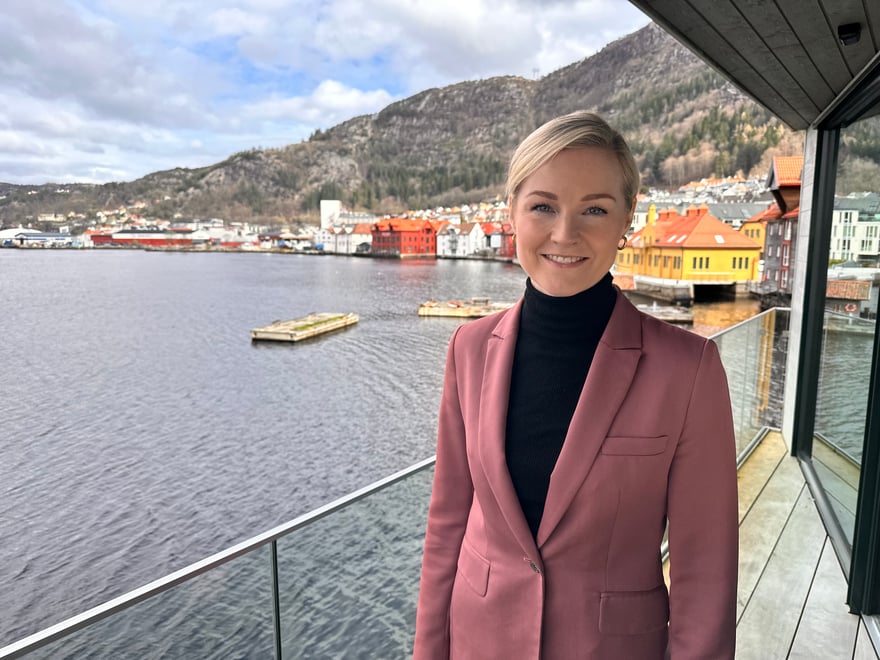 Cathrine i burgunder blazer smiler på brygge foran havet