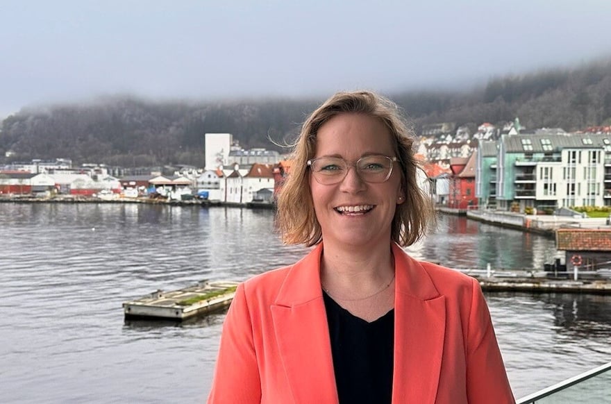 Smilende kvinne (Louise) på brygge i oransje blazer