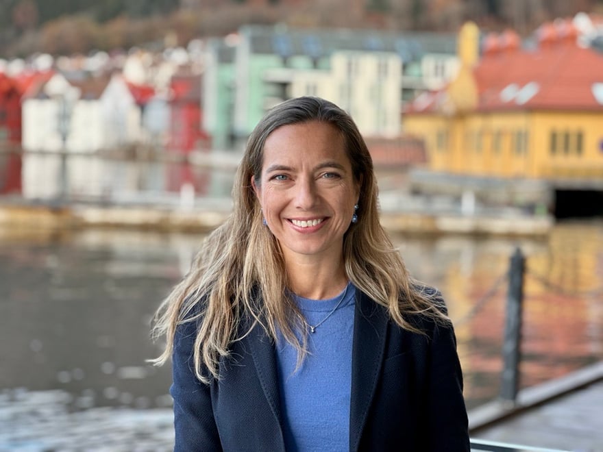 Marianne i blått foran sjø og brygge