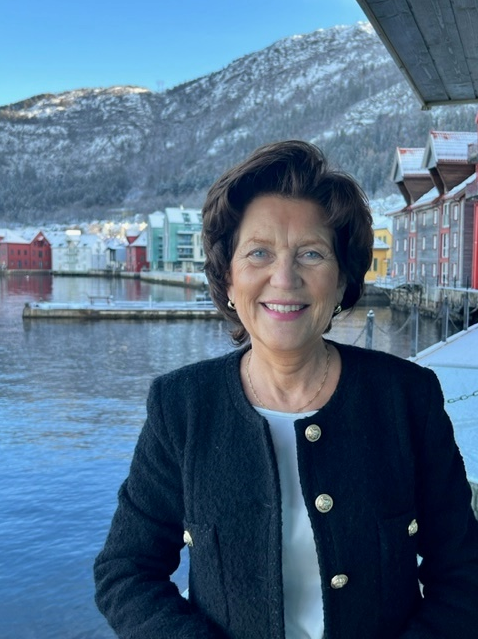 Wenche smiler foran blått hav