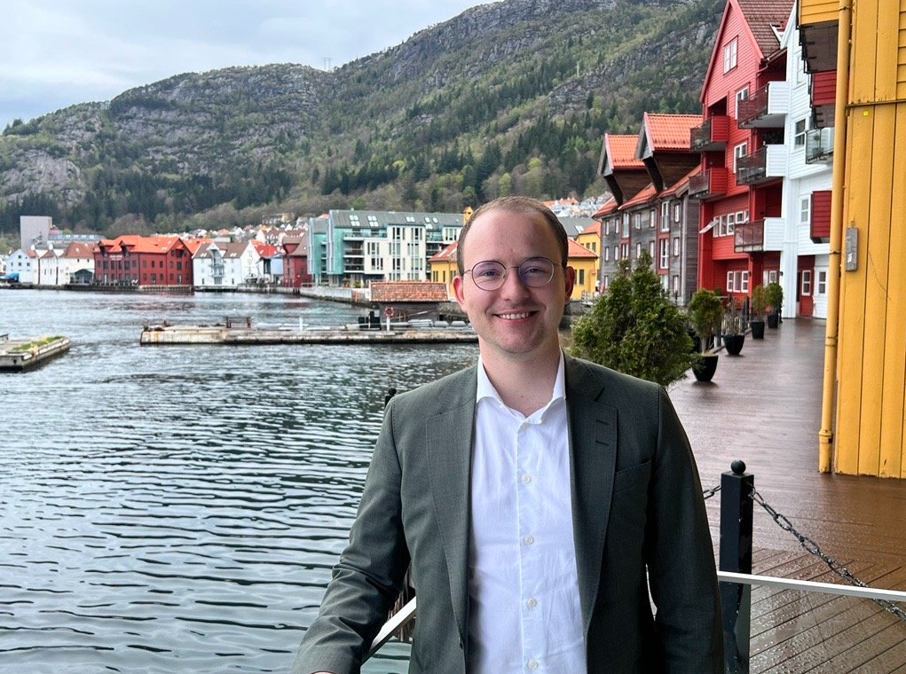 Magnus i grønn dress jakke foran sjø
