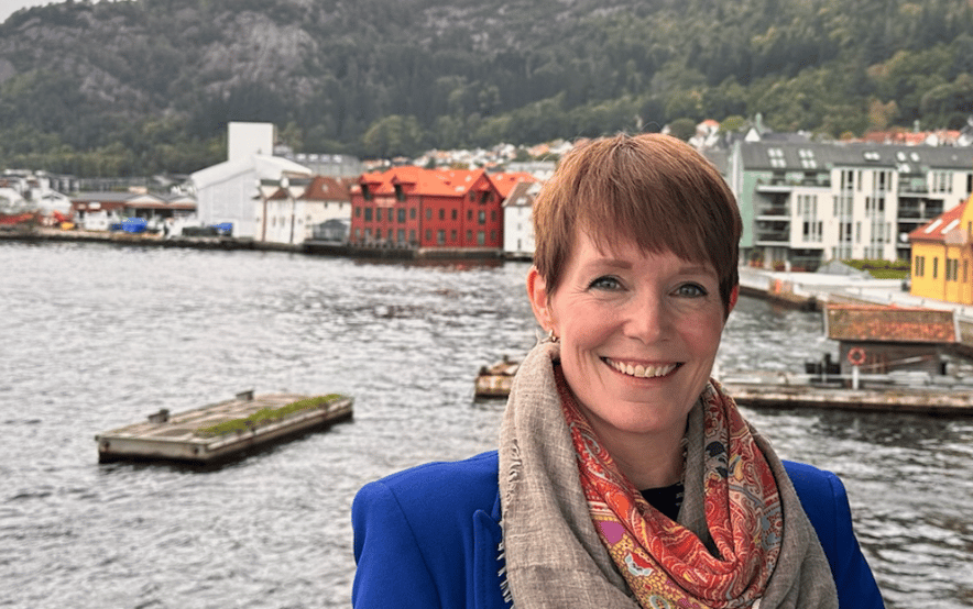 Smilende kvinne (Kristin Helen) på brygge i blå jakke