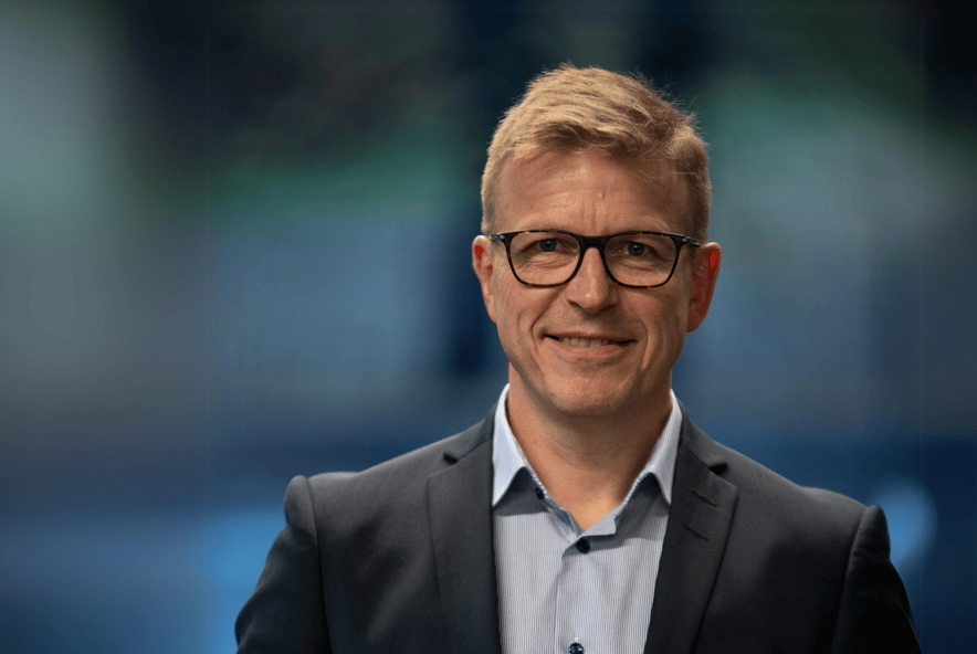 Mann (Knut) i dress foran blå bakgrunn