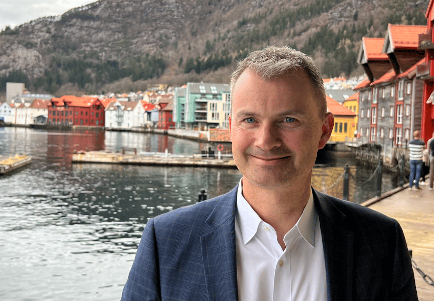 Bilde av smilende mann (Even) i dress på brygge