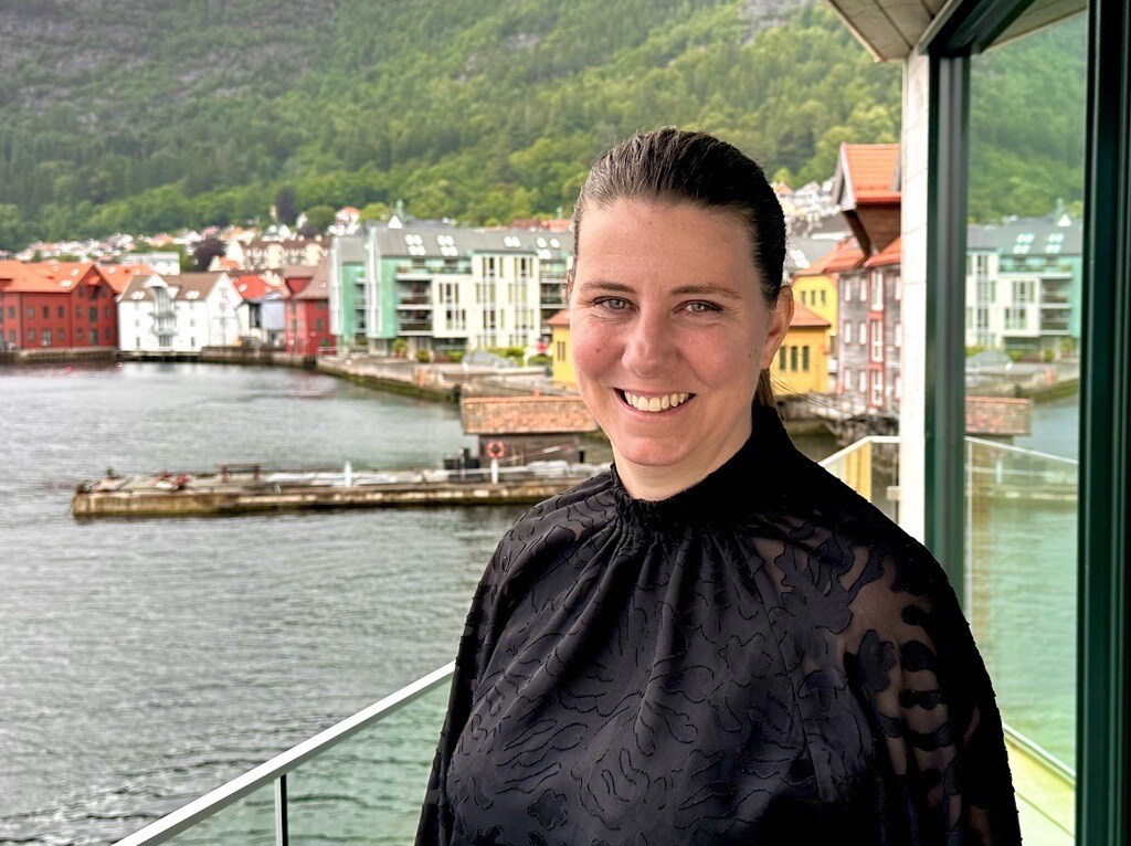 Ingeborg smiler foran havet og brygge