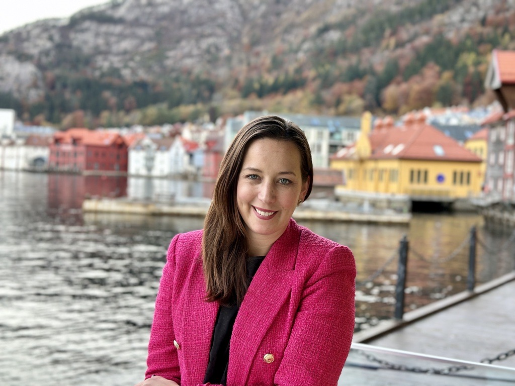 Henriette i rosa dressjakke foran hav og brygge