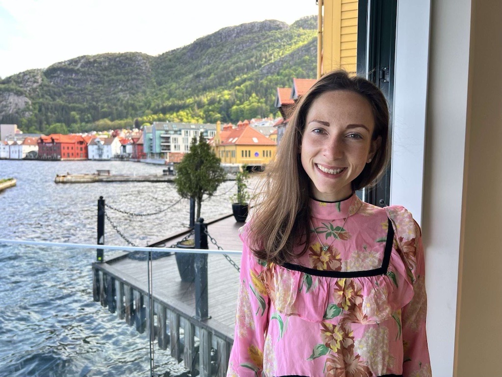 Ingvild smiler i rosa bluse foran brygge