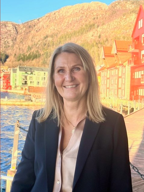 Eva som smiler foran solfylt brygge 